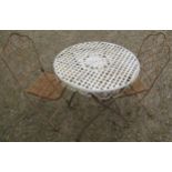 A painted and weathered steel folding garden terrace table of circular form with circular lattice
