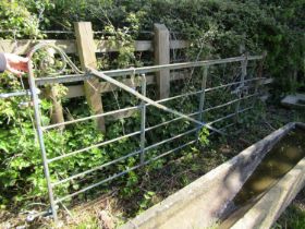 An old painted and weathered heavy iron gate, with horizontal open bars and simple scroll detail (