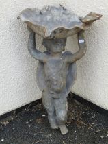 An old lead bird bath in the form of a winged cherub supporting a shell aloft surmounted by a