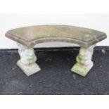 A weathered cast composition stone three sectional garden bench with curved and stepped slab seat