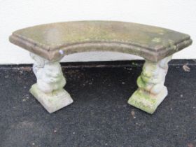 A weathered cast composition stone three sectional garden bench with curved and stepped slab seat