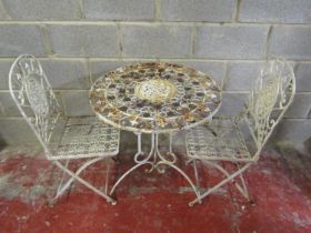 A weathered cream painted three piece iron work terrace set with decorative pierced scrolling