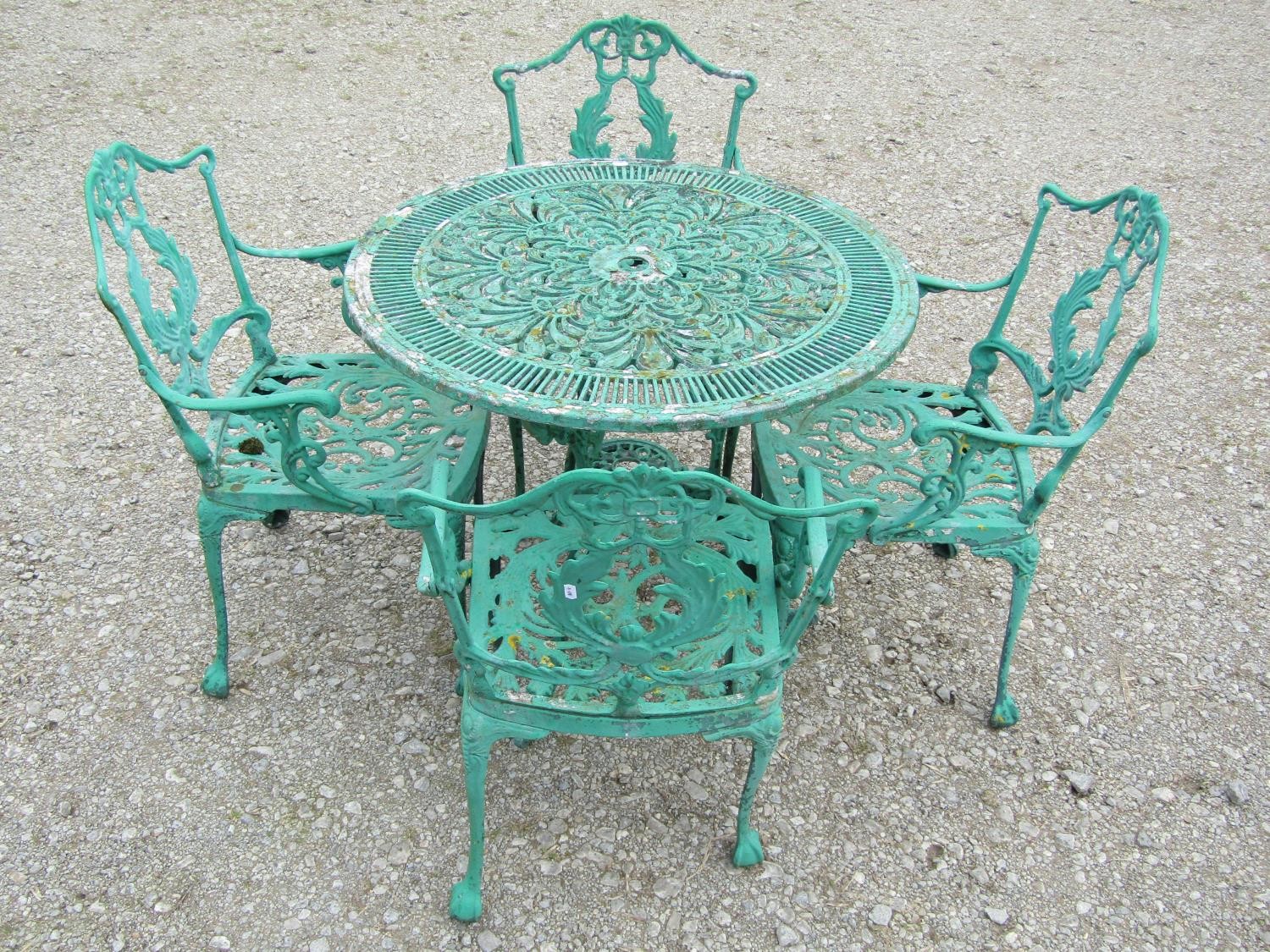 A weathered green painted cast aluminium garden terrace table of circular form with decorative