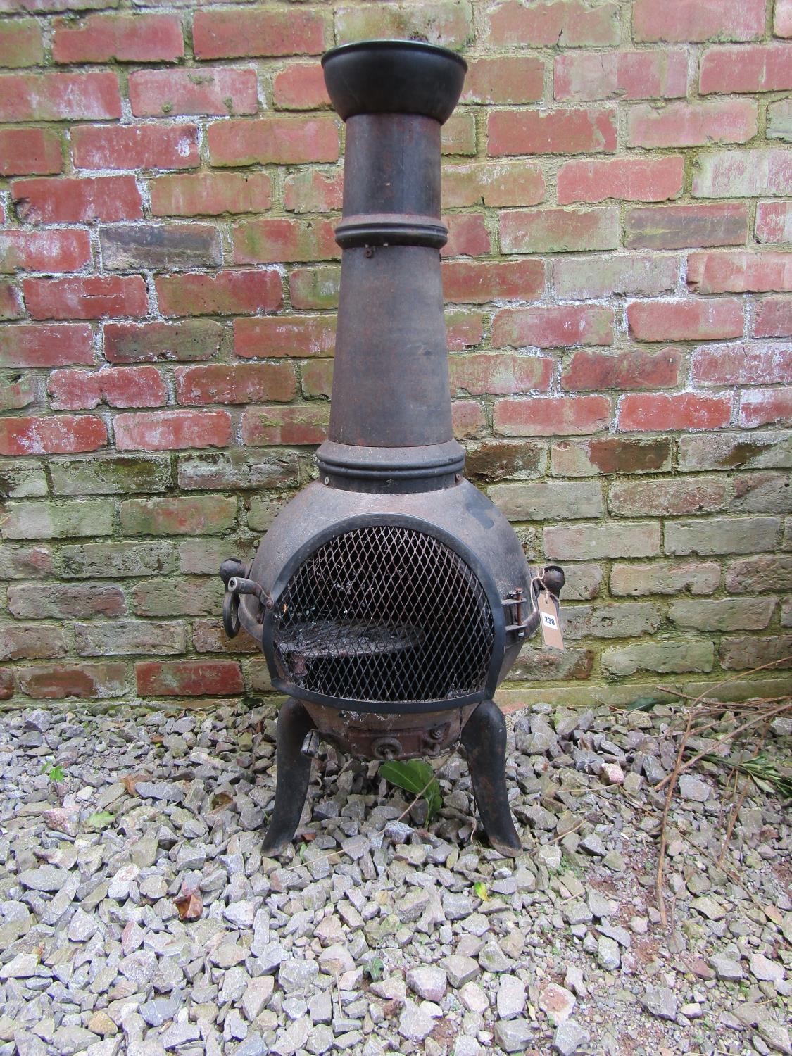 A cast iron chimenea and cover, 110 cm high