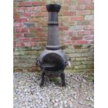 A cast iron chimenea and cover, 110 cm high