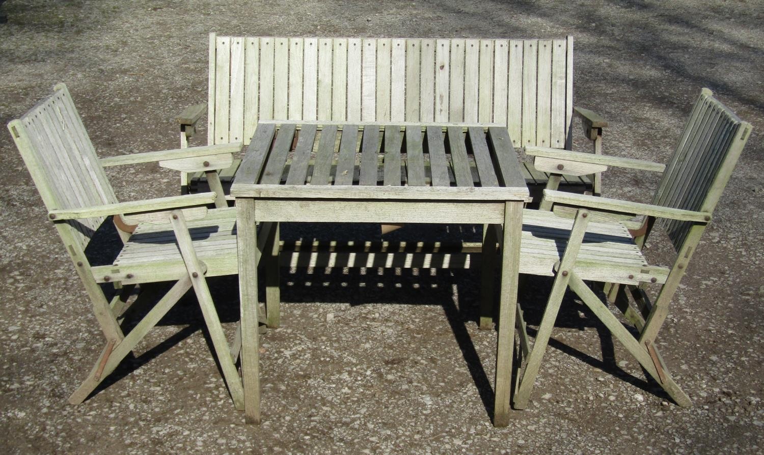 A weathered (silvered) teak garden suite comprising a folding bench with slatted seat and back 141