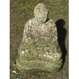 A cast composition stone garden ornament in the form of a seated Buddha in lotus position, raised on