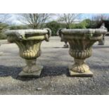 A pair of large weathered cast composition stone garden urns with lobed bodies, fixed ring