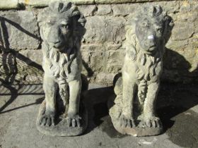 A pair of weathered cast composition stone terrace or pier garden ornaments in the form of seated