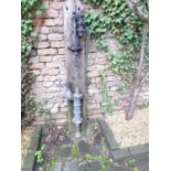 An old weathered cast iron and brass (or possibly bronze) hand lever operated water pump mounted