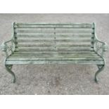 A light green painted garden bench with wooden slatted seat raised on decorative pierced and
