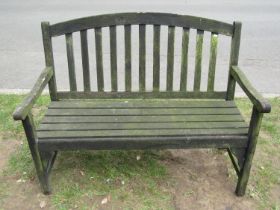 A weathered teak two seat garden bench with slatted seat and back beneath an arched rail 122 cm wide