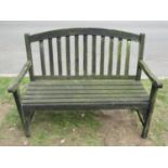 A weathered teak two seat garden bench with slatted seat and back beneath an arched rail 122 cm wide
