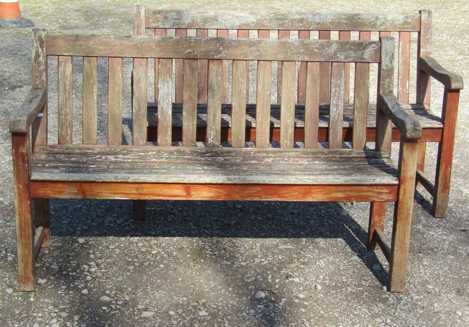 A pair of good quality heavy gauge weathered teak three seat garden benches with slatted seats and
