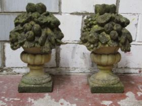 A pair of weathered two sectional cast composition stone garden ornaments in the form of fruiting