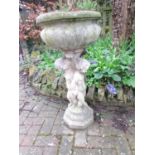 A weathered cast composition stone planter with circular lobed bowl set on a pedestal of three