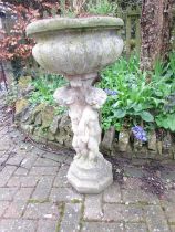 A weathered cast composition stone planter with circular lobed bowl set on a pedestal of three