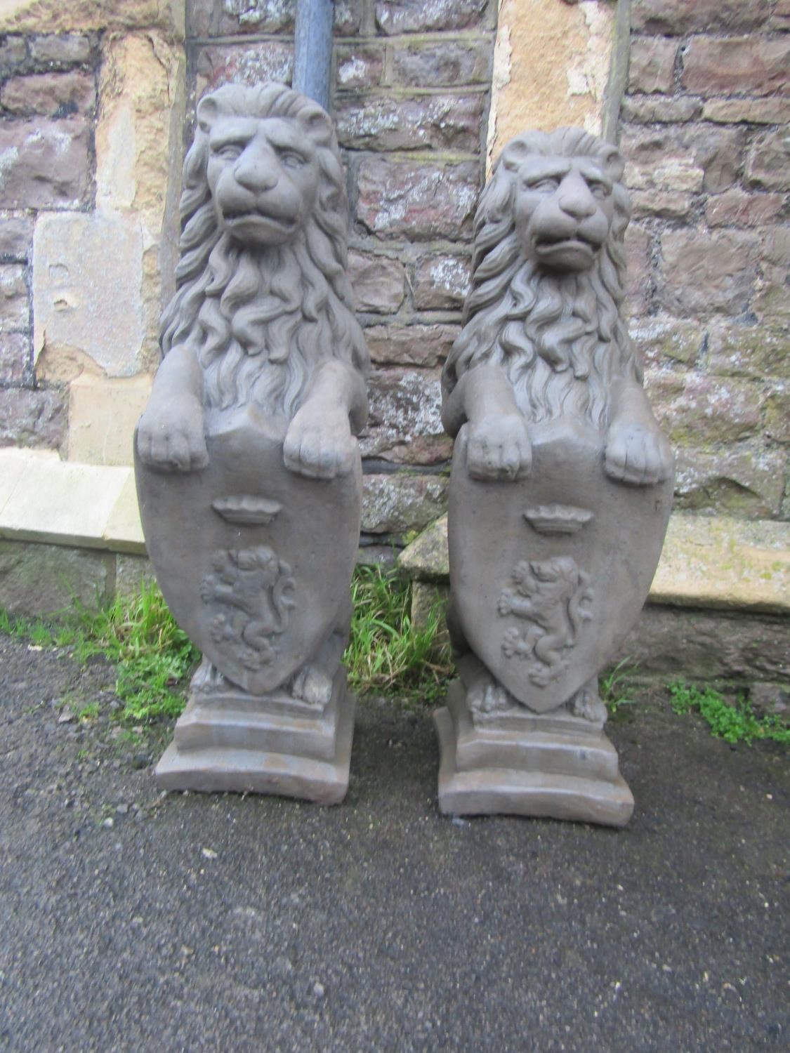 A pair of cast composition stone pier/garden ornaments in the form of seated lions clutching - Image 2 of 3