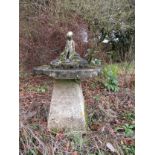 A reconstituted bird bath, circular with a boy peering into the depths raised on an earlier