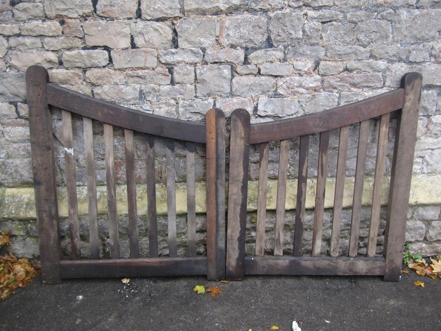 Pair of simple weathered oak entrance gates with open vertical slats, supporting down swept