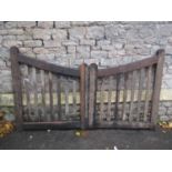 Pair of simple weathered oak entrance gates with open vertical slats, supporting down swept