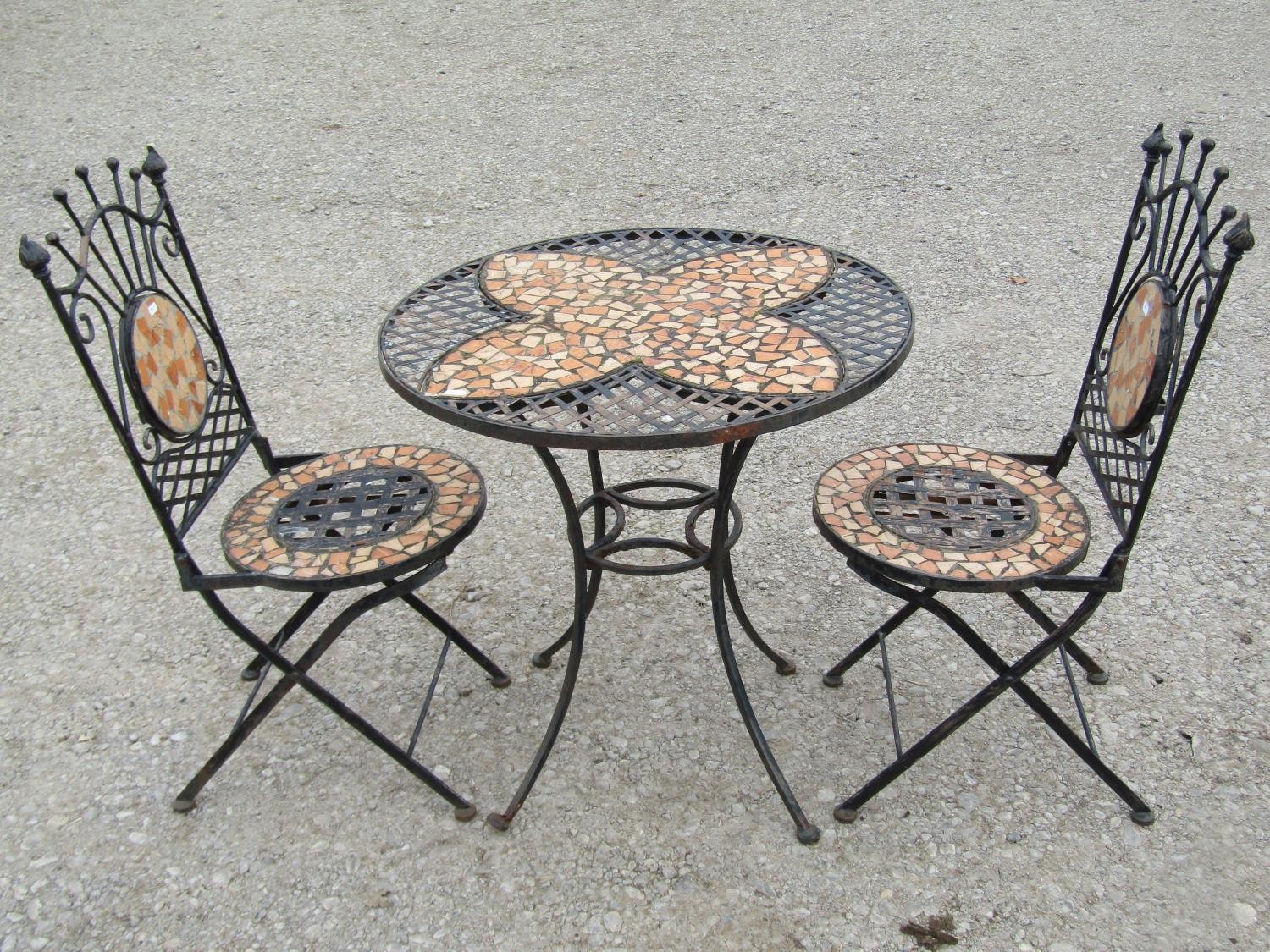 A heavy gauge three piece iron work Bistro table and two chairs with mosaic panels, lattice and