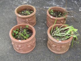 A matched set of four weathered squat cylindrical terracotta planters with repeating raised relief