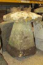 A weathered carved natural stone staddle stone and associated cap, 70cm high, 60cm diameter.