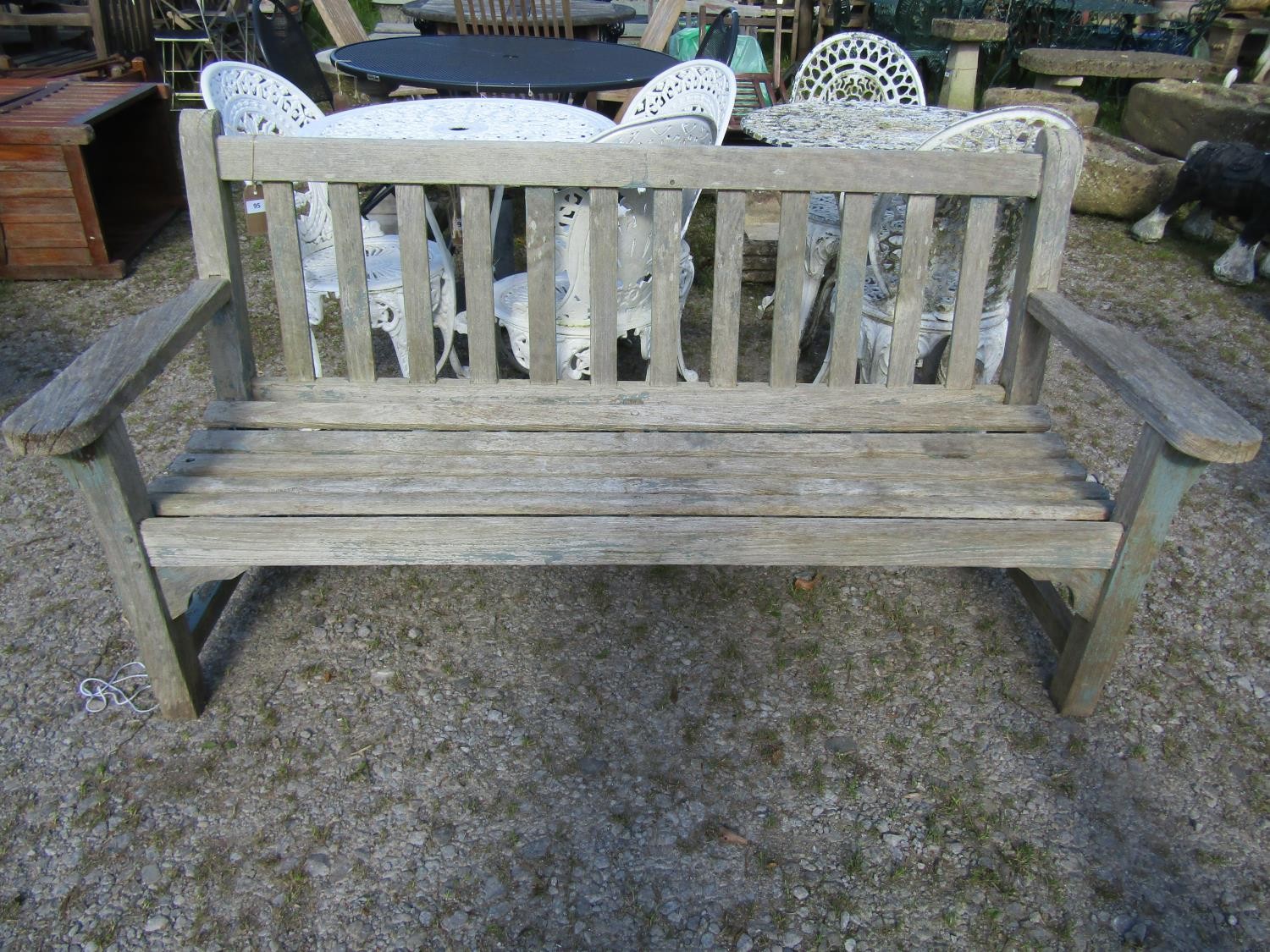 A weathered teak garden bench with slatted seat and back, with traces of painted finish, 162cm