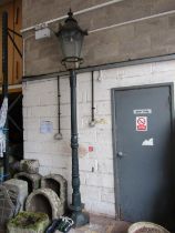 A Victorian style cast iron lamp post with hexagonal tapered hood raised on a partially fluted