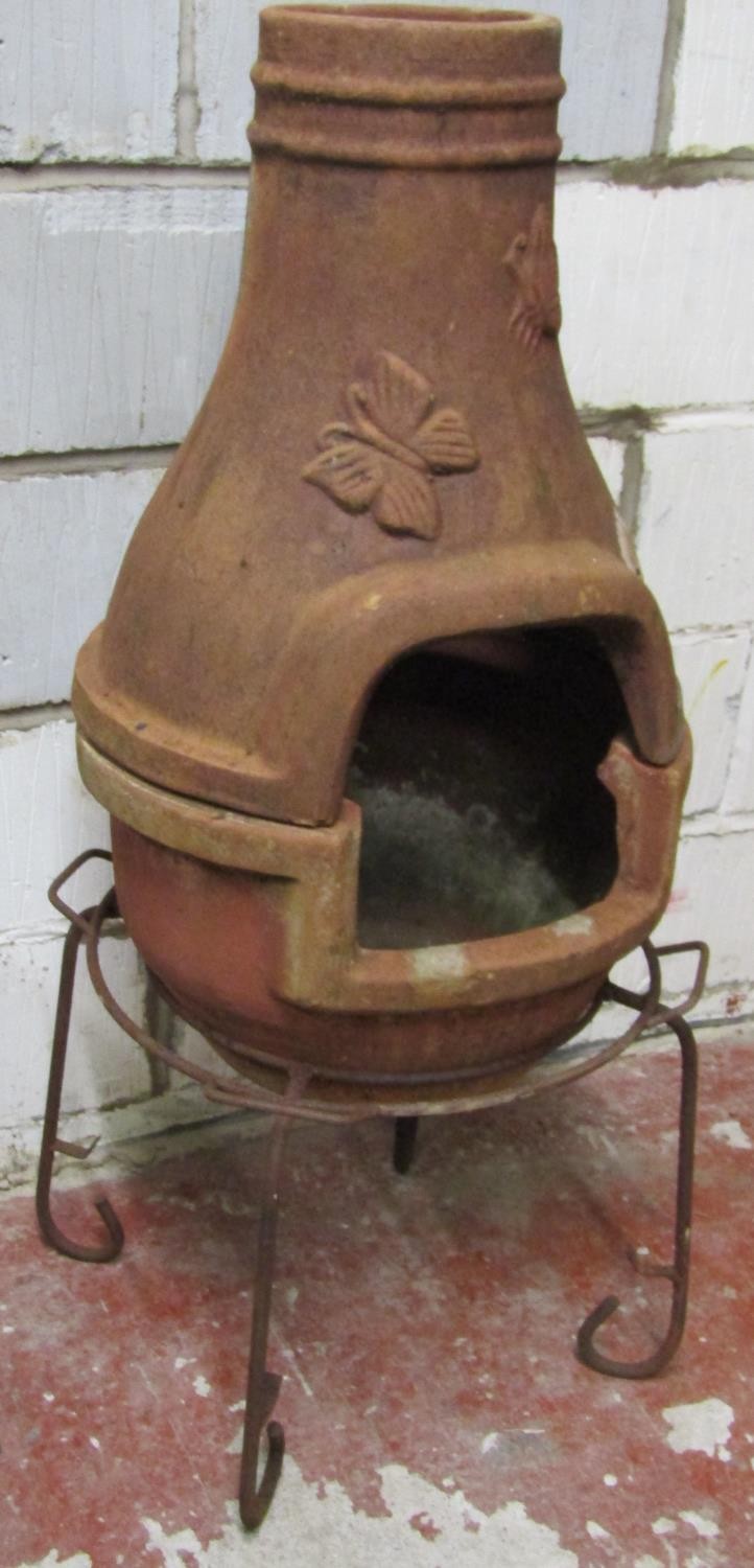 A weathered clay two sectional chimenea with moth and butterfly relief detail and raised on a - Image 3 of 4