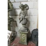 A weathered cast composition stone cherub astride a sphere clutching a floral garland raised on a