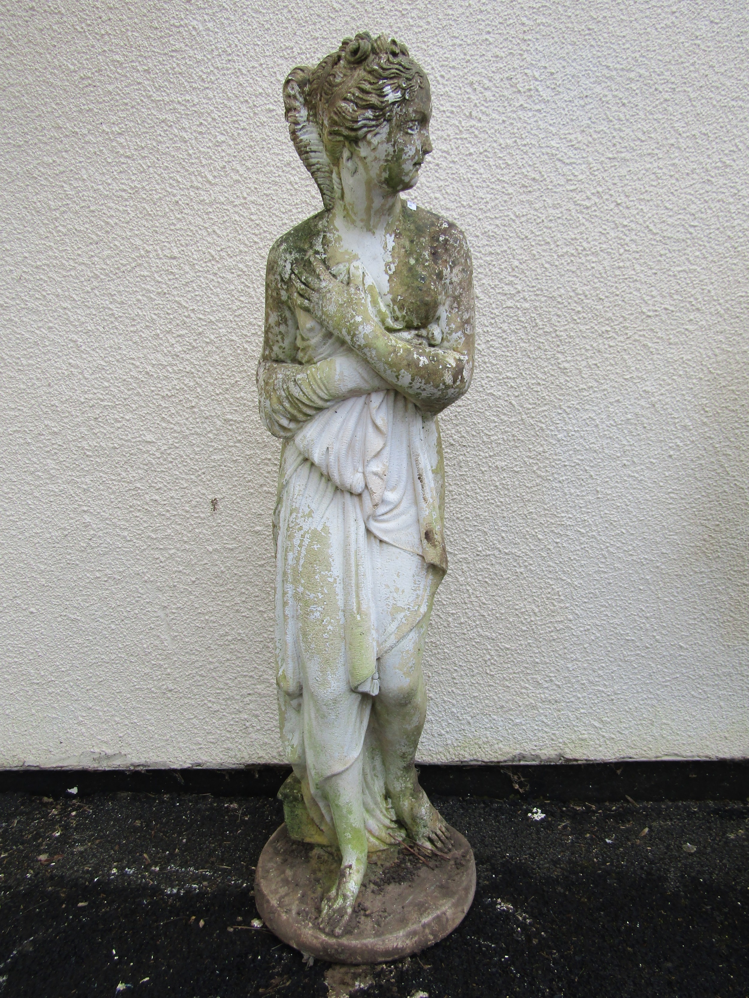 A partially painted and weathered cast composition stone garden ornament in the form of a standing