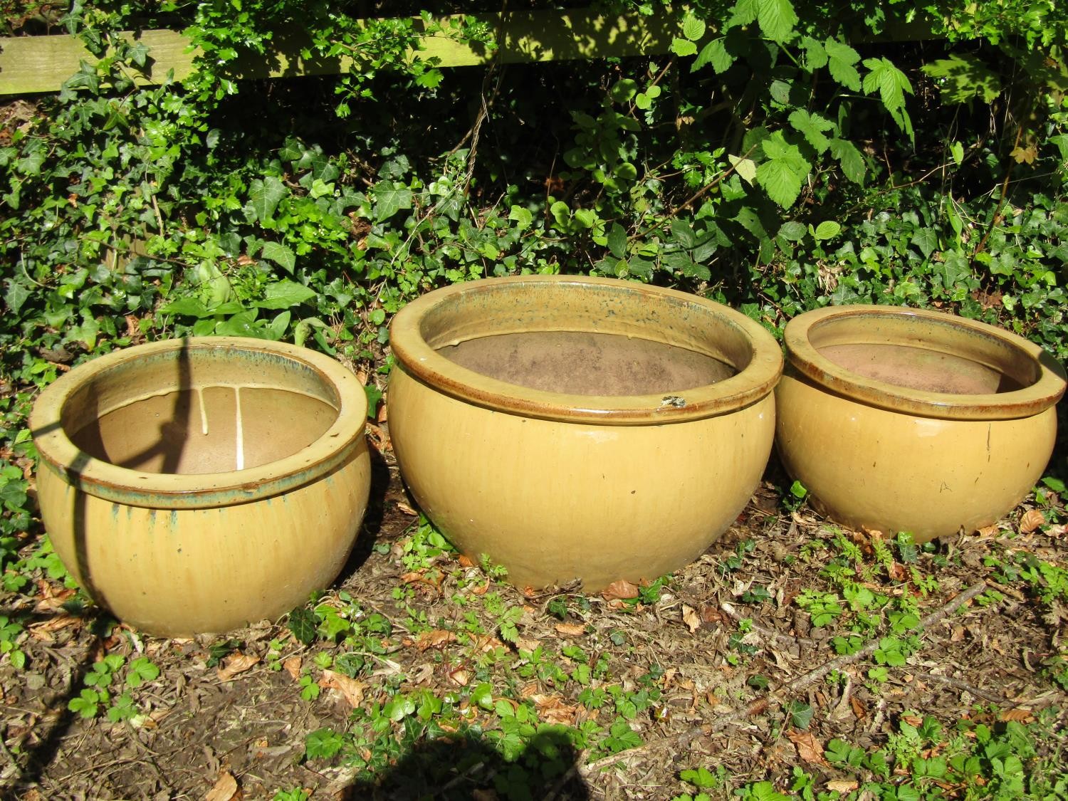 Four contemporary light brown glazed squat oviform planters of varying size, the largest example