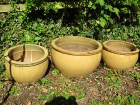 Four contemporary light brown glazed squat oviform planters of varying size, the largest example