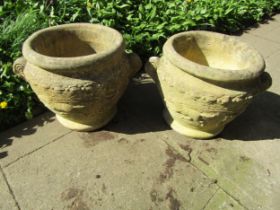 A pair of weathered cast composition stone roman type urns, the circular bowls with fixed scrolled