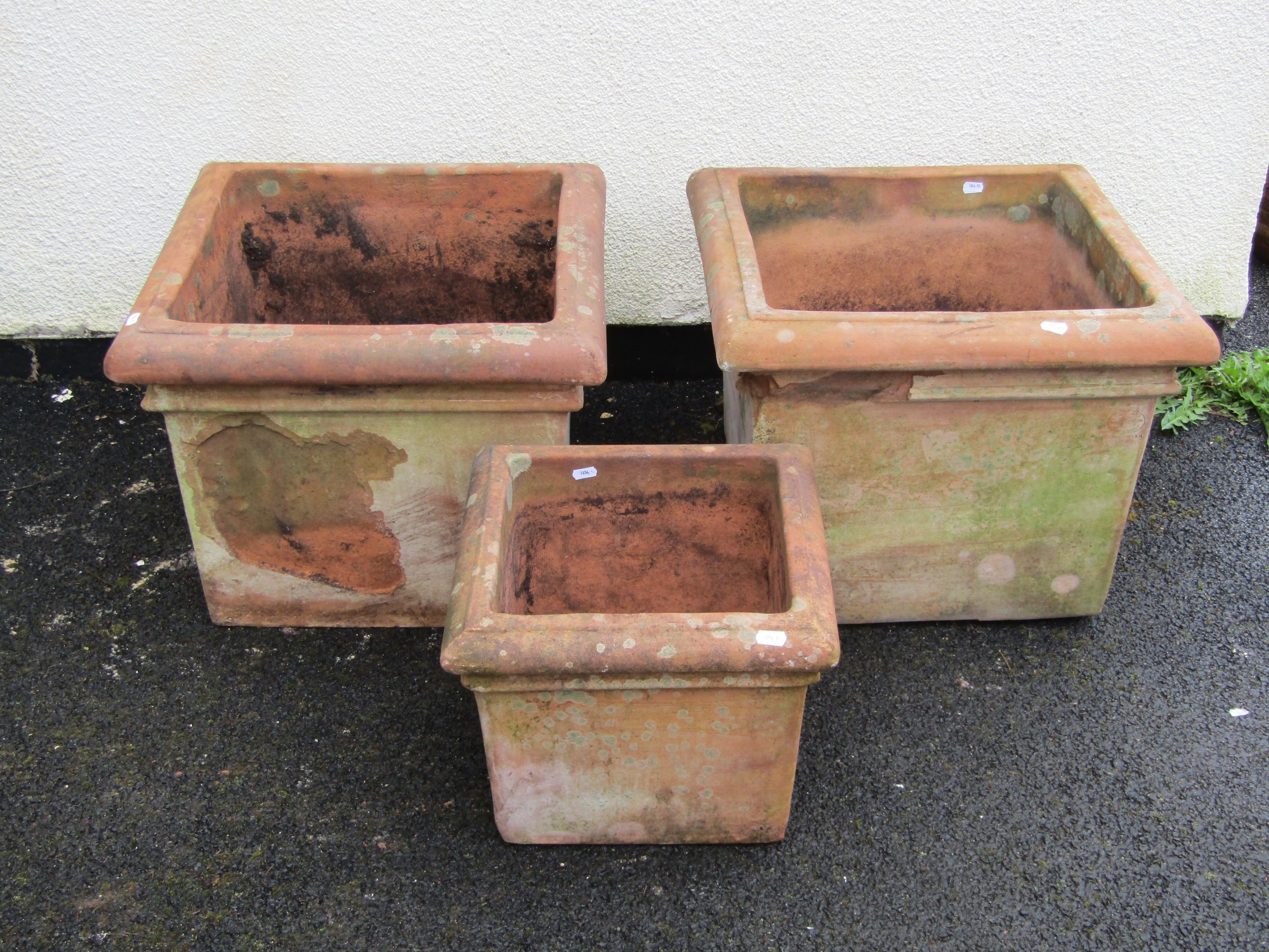 A pair of weathered terracotta planters of square cut form with moulded rims 42 cm high x 53 cm