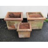 A pair of weathered terracotta planters of square cut form with moulded rims 42 cm high x 53 cm