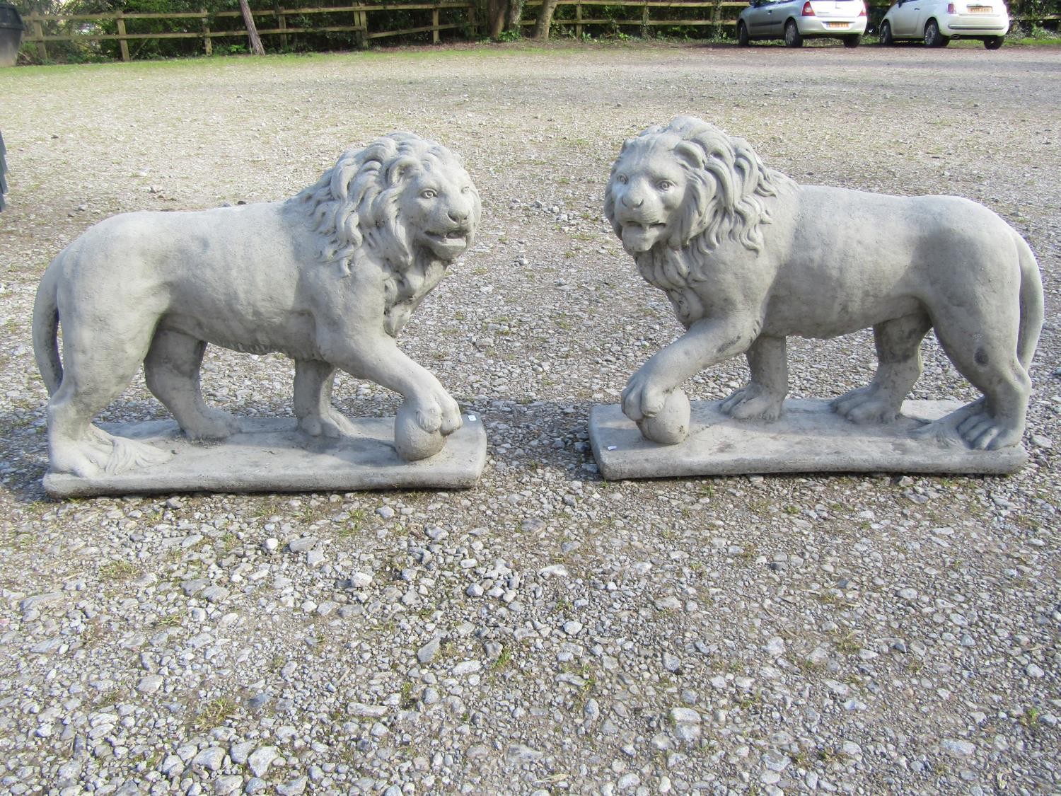 A pair of cast composition stone garden terrace/pier ornaments in the form of standing lions, 58