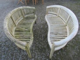 A pair of weathered teak banana shaped garden benches 160 cm wide