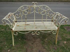 A weathered cream painted two seat metal bench loosely in the Regency style with shaped outline