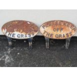Two weathered cast iron oval 'Keep Off The Grass' signs together with a small cast iron drain cover,
