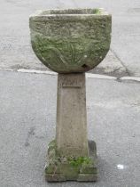 A weathered cast composition stone garden planter of square tapered and rounded form with floral