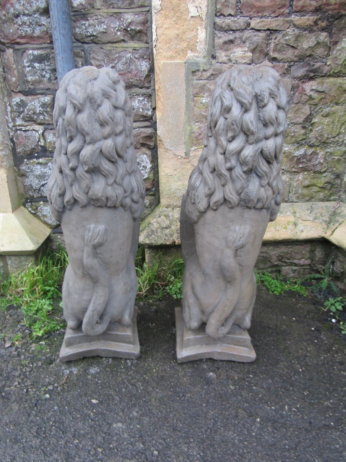 A pair of cast composition stone pier/garden ornaments in the form of seated lions clutching - Image 3 of 3