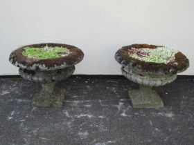 A pair of weathered cast composition stone garden urns, the squat circular lobed bowls with flared