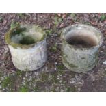 A pair of weathered cast composition stone squat cylindrical planters with repeating classical
