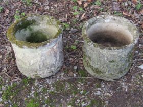 A pair of weathered cast composition stone squat cylindrical planters with repeating classical