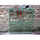 A heavy gauge Victorian green iron garden gate with open bars, spear head finials and scroll detail,