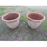 A pair of large weathered terracotta planters of circular tapered and simple ribbed form, 56 cm high