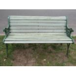 A two seat garden bench with painted wooden slatted seat raised on decorative pierced cast iron